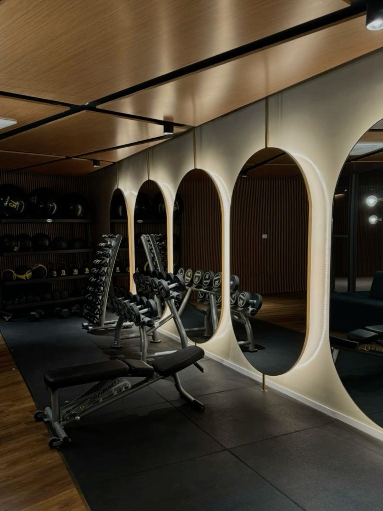 Espace musculation avec haltères, banc et miroirs dans le club premium HPO Paris Le Marais
